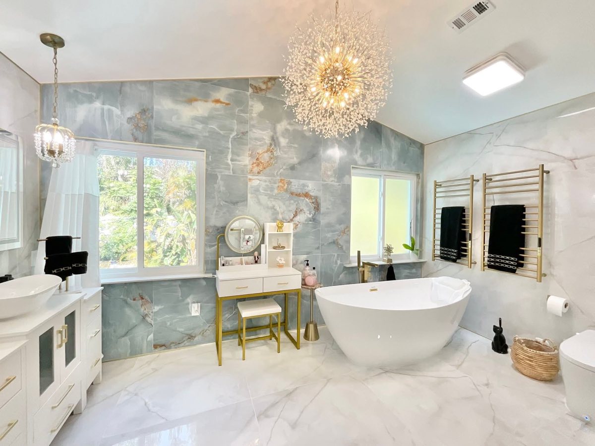 Bathroom with a freestanding tub, chandelier and marble-look walls