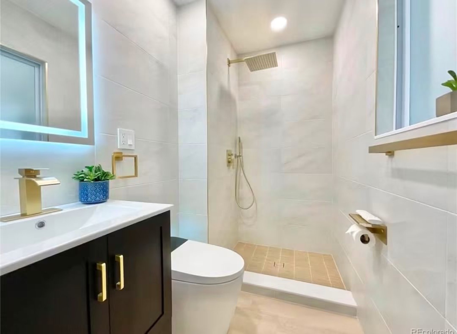 Bathroom with a tiled walk-in shower and dark vanity with gold handles
