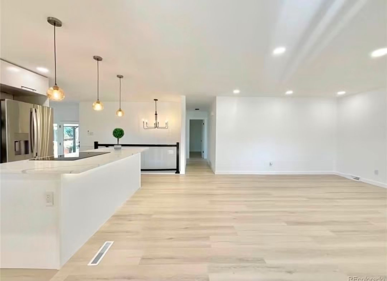 Open kitchen and living area with a white island and light flooring
